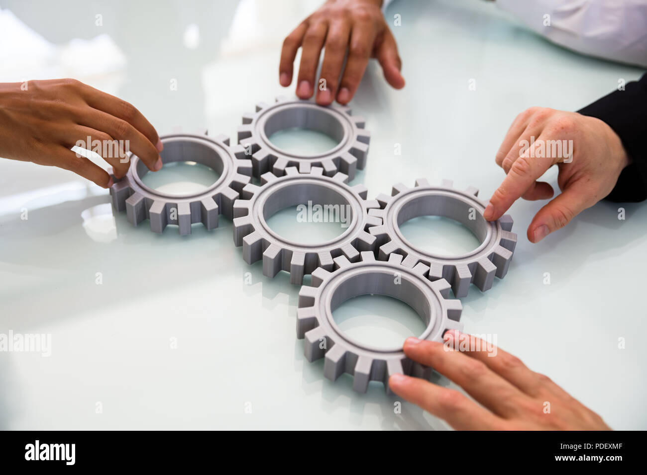 Close-up's Business Menschen Hand verbinden Zahnräder auf Schreibtisch Stockfoto