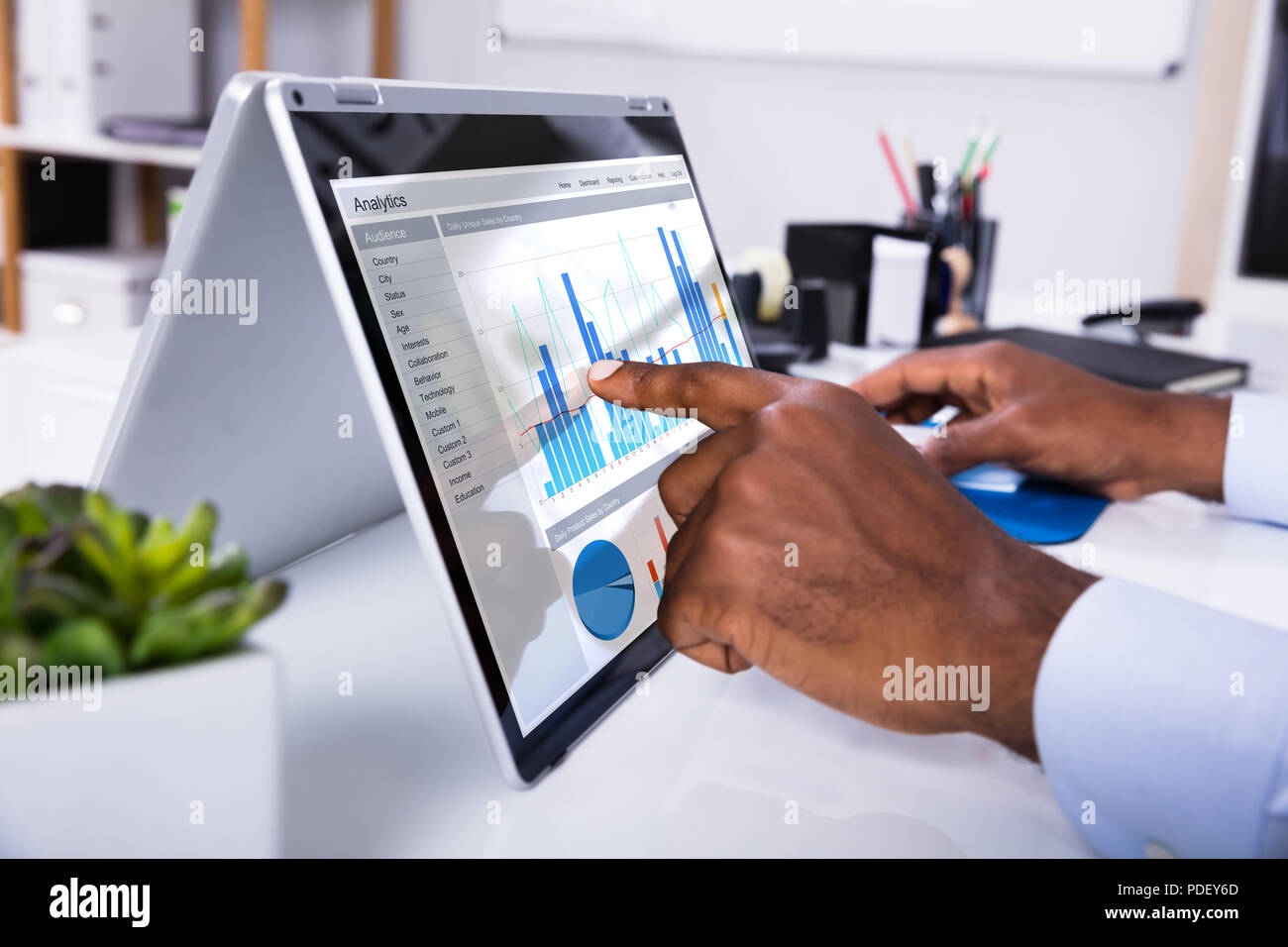 Der Geschäftsmann Zeiger auf dem Laptop Bildschirm mit Grafik über den Schreibtisch Stockfoto