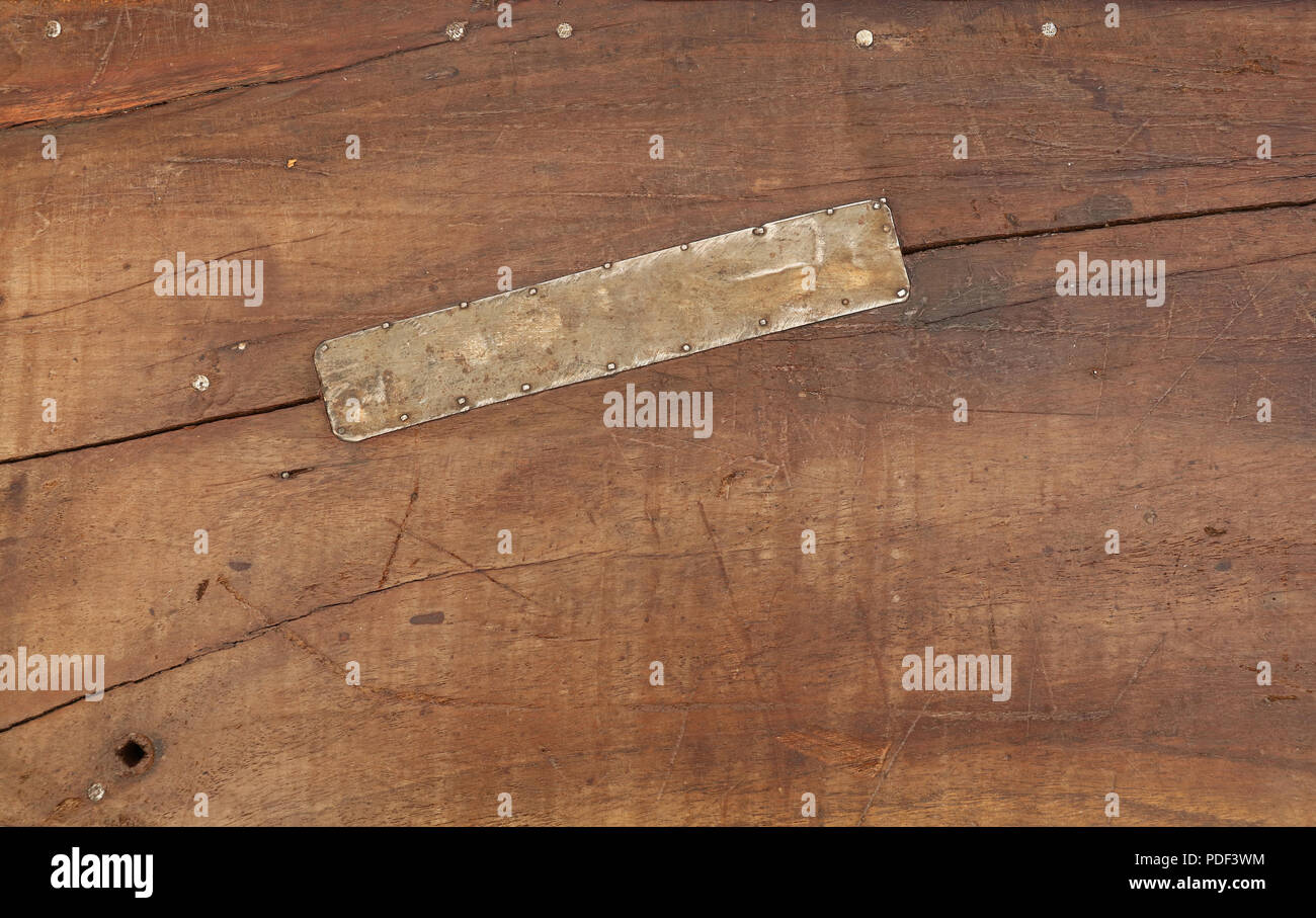 Grunge Hintergrund Textur von braunem Holz mit schmutzigen Flecken, Kratzer, Risse und genagelt Zinnmetall Patch, in der Nähe Stockfoto