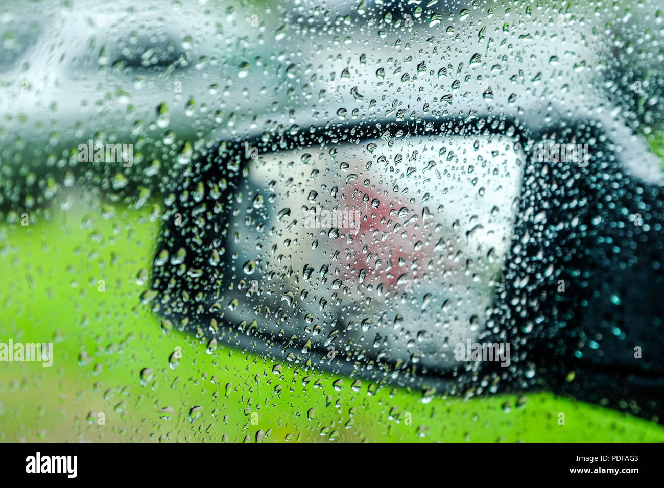 Wassertropfen oder Regen fällt auf das Auto Glas. Unscharfer Hintergrund. Flanke. Auto Spiegel im Hintergrund. Stockfoto