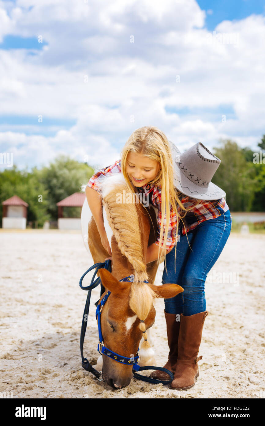 Gutherzig Schülerin spielen mit kleinen niedlichen Pony mit Geflecht Stockfoto