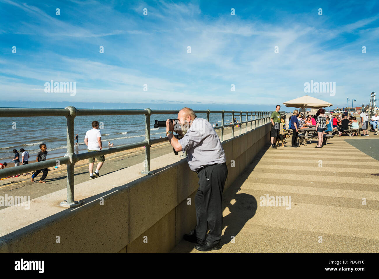 Ein bärtiger Mann die Bilder mit einer Nikon P900, Coolpix an einem sonnigen Tag am Strand, Prestatyn, Wales, UK. Stockfoto