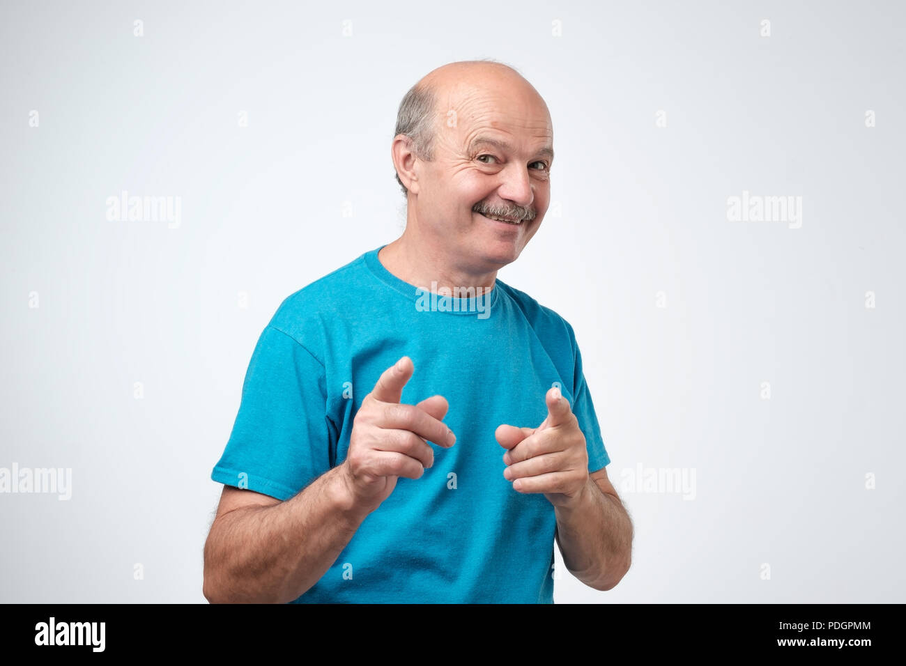 Aufgeregt reifer Mann im blauen Hemd, die Finger von der Kamera auf einem weißen Hintergrund isoliert Stockfoto