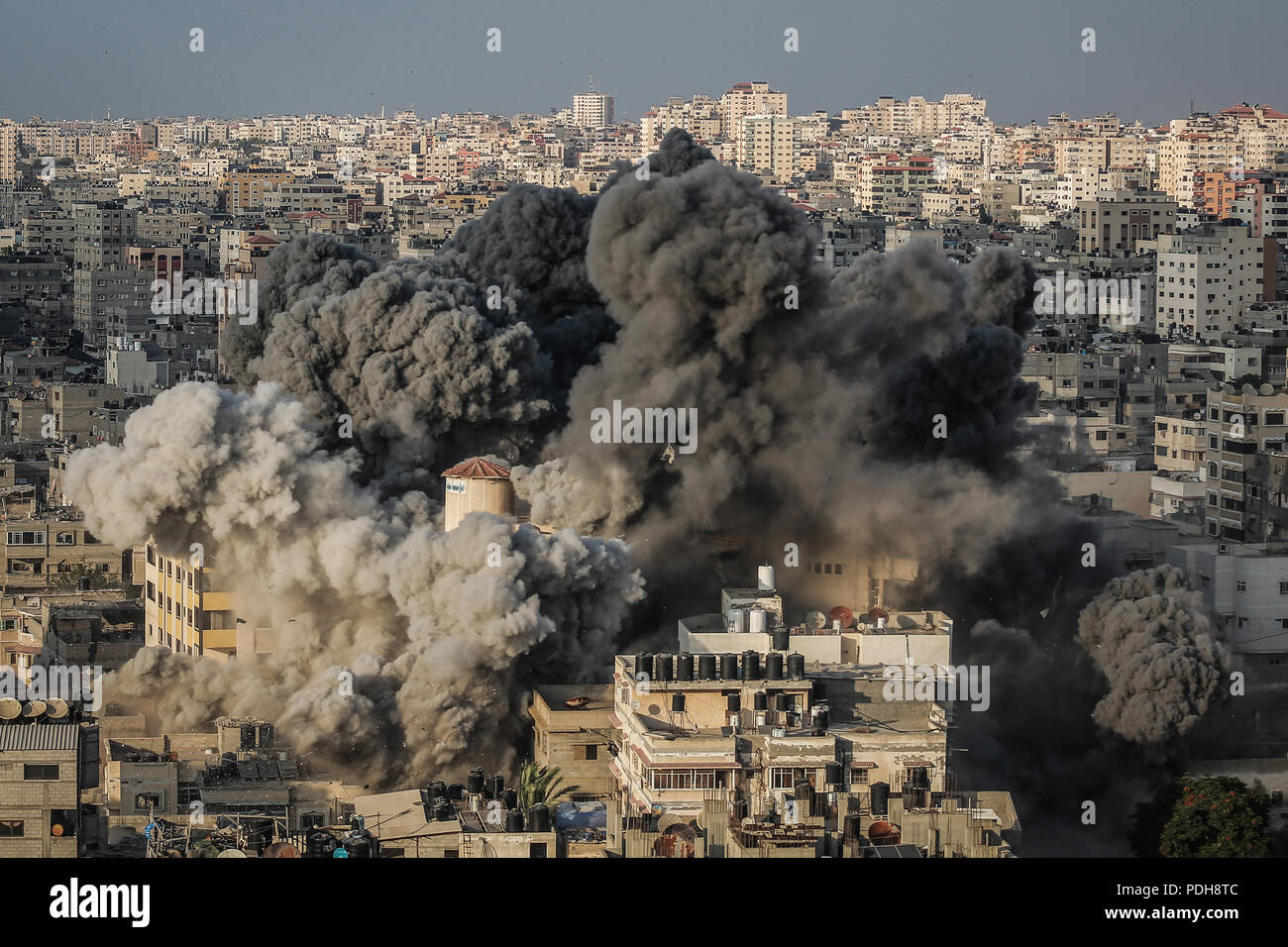 Gaza, Gazastreifen. 09 Aug, 2018. Rauch steigt aus einem mehrstöckigen Gebäude nach wurde es durch ein israelisches Flugzeug in Gaza, Gazastreifen, 09. August 2018 bombardiert. Nach Angaben der israelischen Armee, hat Israel eine Welle von Luftangriffen auf den Gazastreifen als Reaktion auf mehr als 180 Raketen und Mörsergranaten auf Israel abgefeuert wurde, und Geschützfeuer früheren Mittwoch, dass gezielte zivile Bauarbeiter auf der Grenze zum Gazastreifen eingeleitet. Credit: Emad Awad/dpa/Alamy leben Nachrichten Stockfoto
