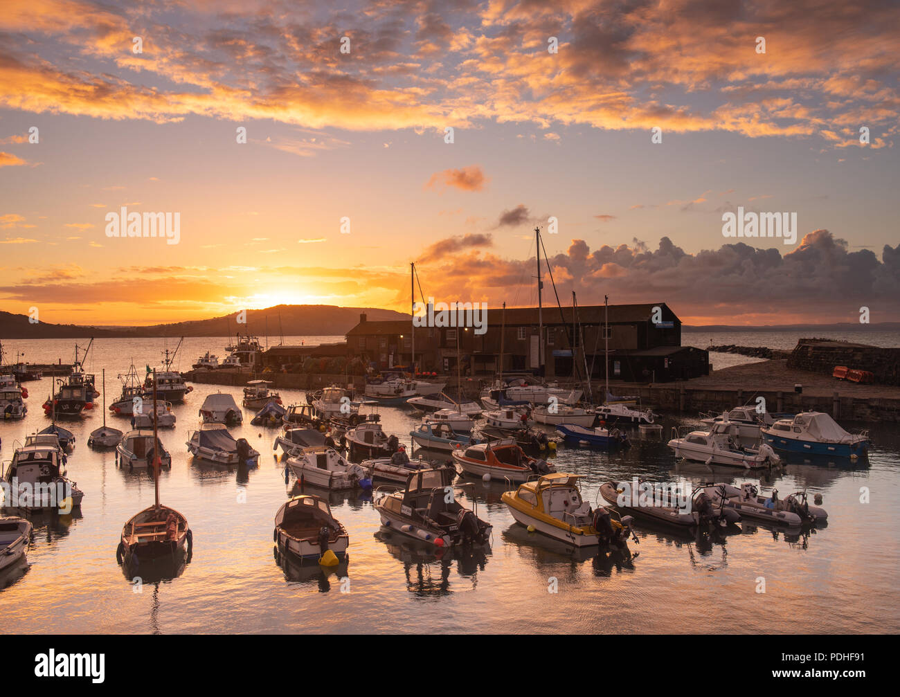 Lyme Regis, Dorset, Großbritannien. 10. August 2018. UK Wetter: spektakulären Sonnenaufgang Farben bei der Küstenstadt Lyme Regis. Der Himmel über dem historischen Cobb Hafen glüht vor Gewitter und kräftige Schauer rot und orange. Credit: Celia McMahon/Alamy Leben Nachrichten. Stockfoto