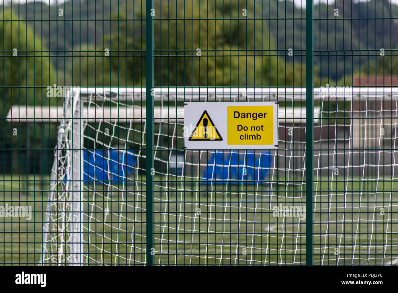 Anmelden Warnung vor Gefahr auf ein stabiles Gitter Zaun mit fußballtor Beiträge sichtbar hinter dem Zaun Stockfoto