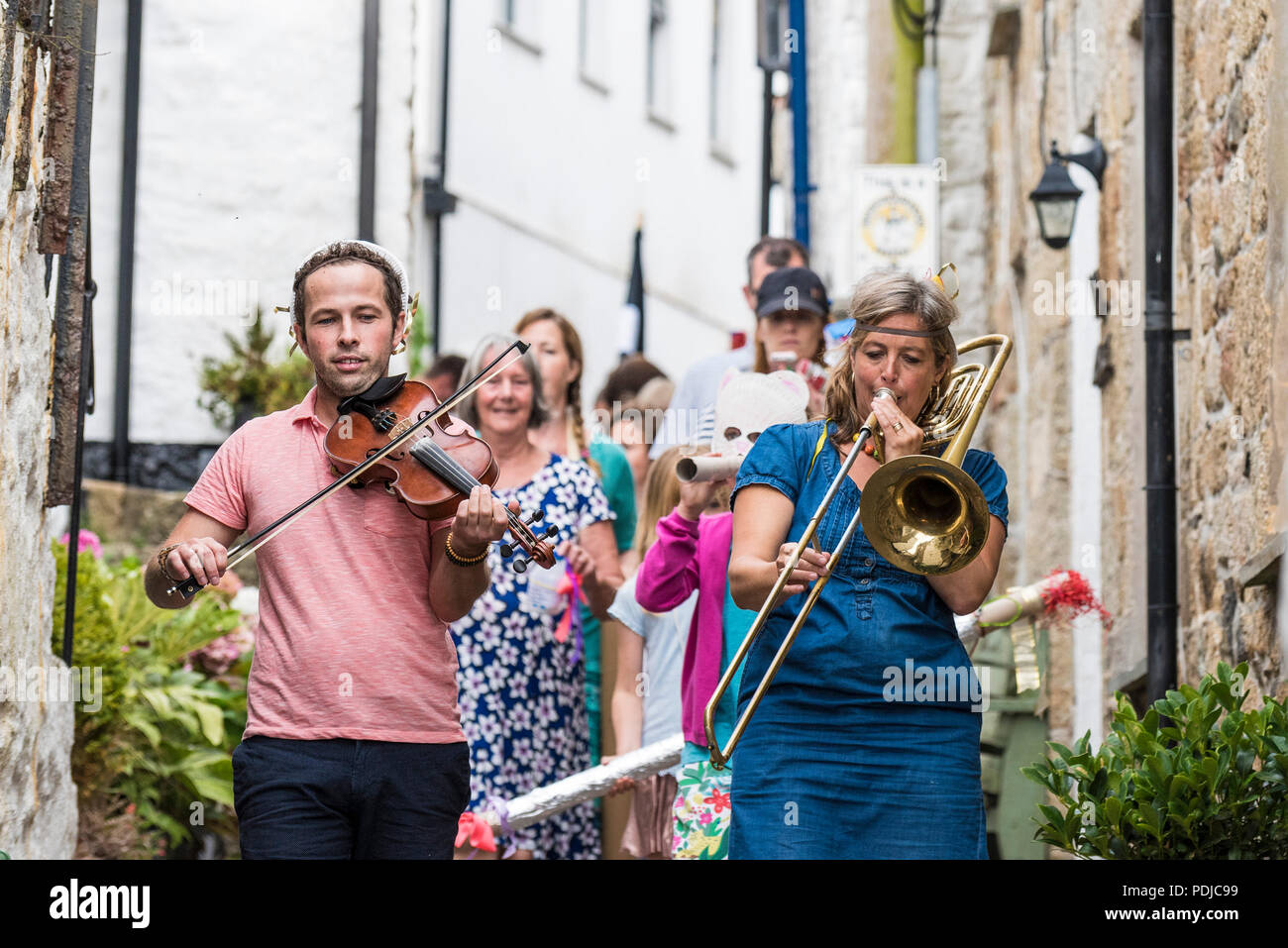 Zwei Musiker Führen einer kleinen Prozession durch die Straßen von Mousehole in Cornwall. Stockfoto