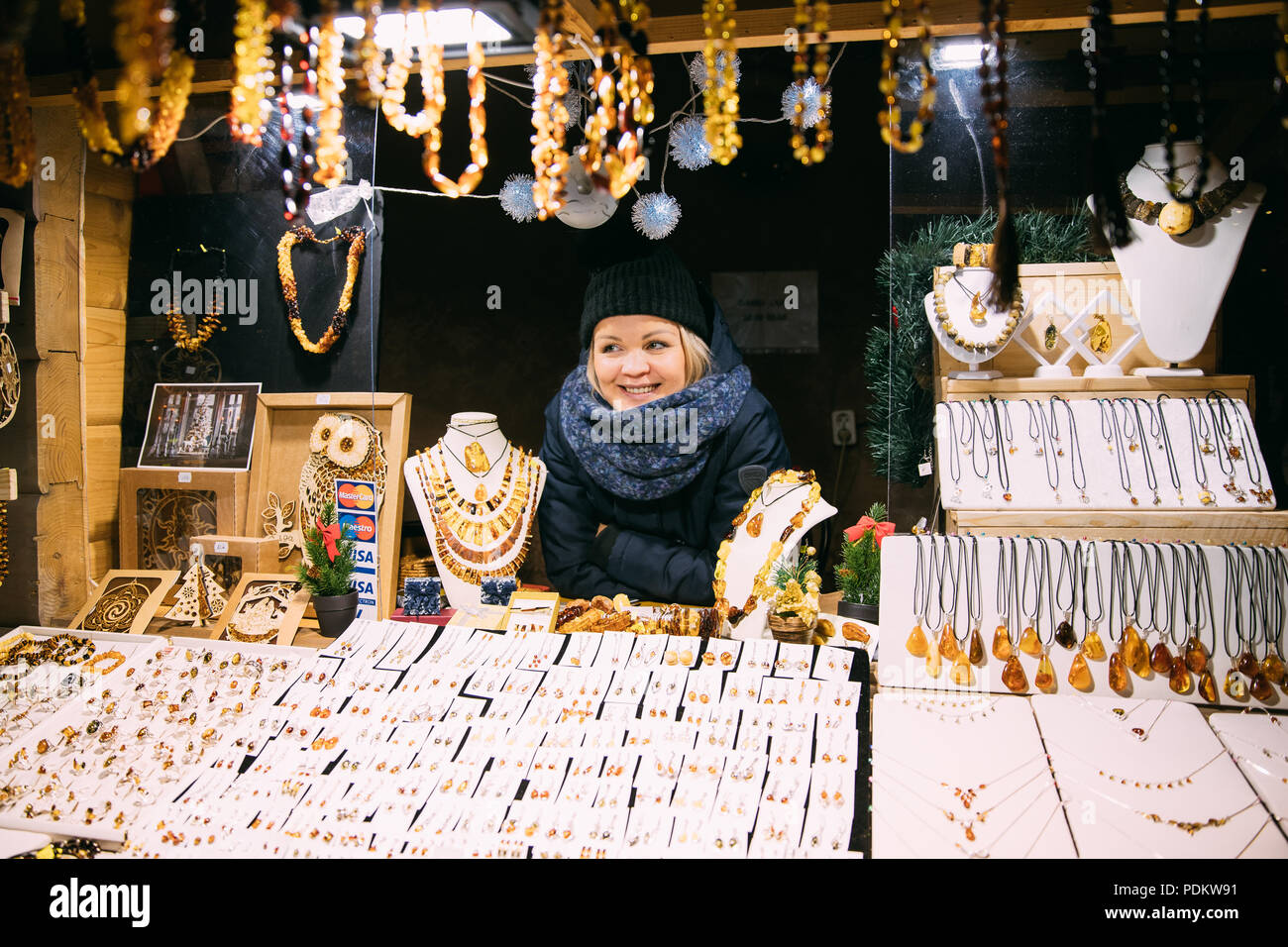 Riga, Lettland - 18 Dezember, 2017: Junge Frau Verkäufer verkauft verschiedene Schmuck aus Bernstein. Traditionelle Souvenirs am europäischen Markt. Souvenir aus Balt Stockfoto