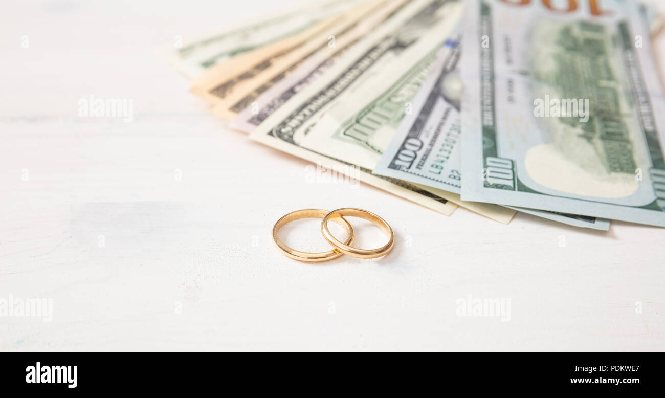 Ehe und Aufwendungen Konzept. Goldene Hochzeit Ringe und Banknoten Dollar isoliert, auf einem weißen Hintergrund Holz, kopieren. Stockfoto