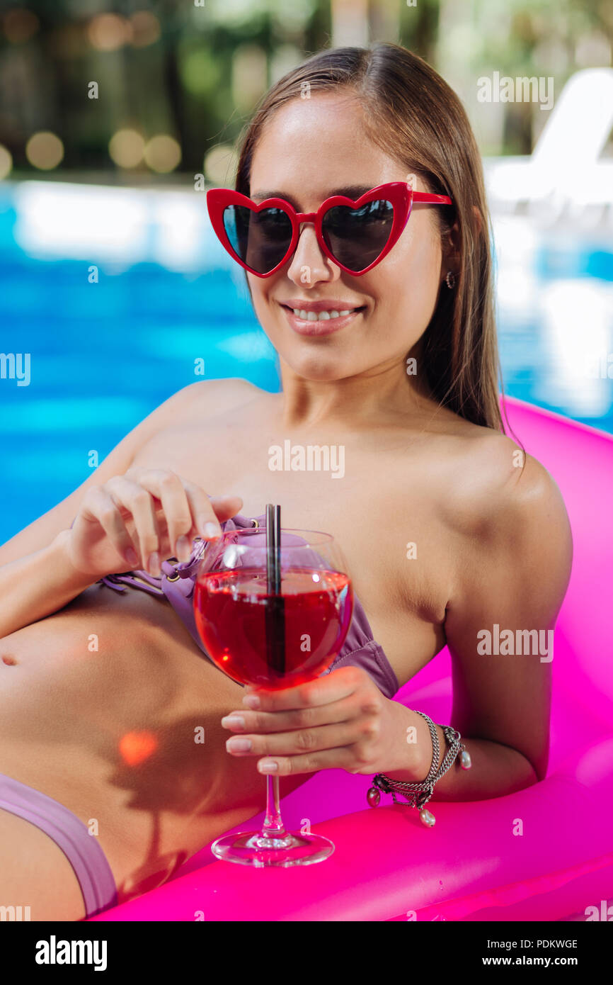 Stilvolle Frau Helle rote Sonnenbrille liegen auf Luftmatratze Stockfoto