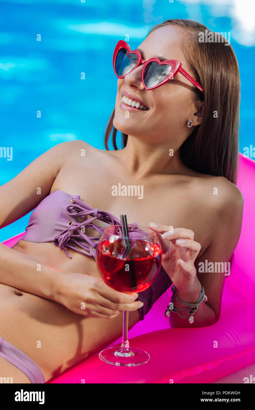 Glückliche Frau Liegewiese beim Liegen auf der Luftmatratze im Pool Stockfoto