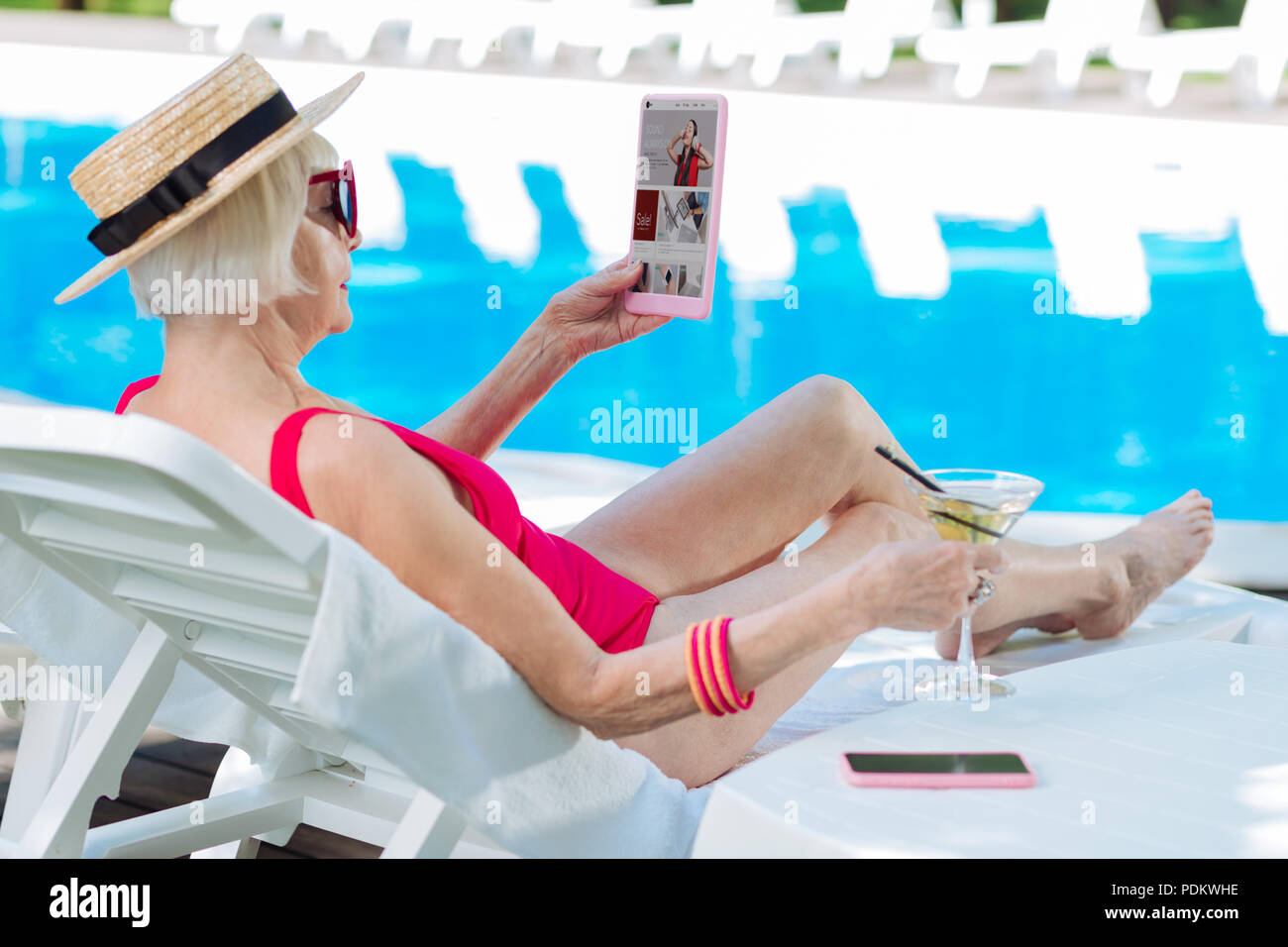 Reife Frau das Tragen der roten Badeanzug ansehen Fotos auf dem Laptop Stockfoto