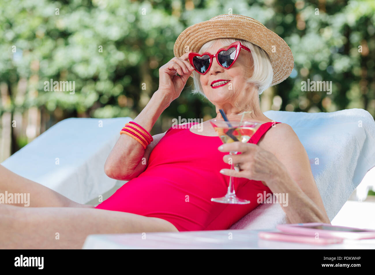 Reife Frau Gefühl glücklich, während der Rest in der Nähe von Pool Stockfoto