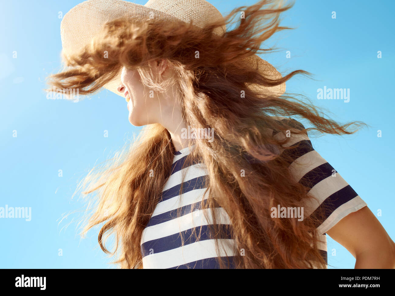 Trendy Frau in Stroh Hut mit flatternden Haare gegen den blauen Himmel Stockfoto