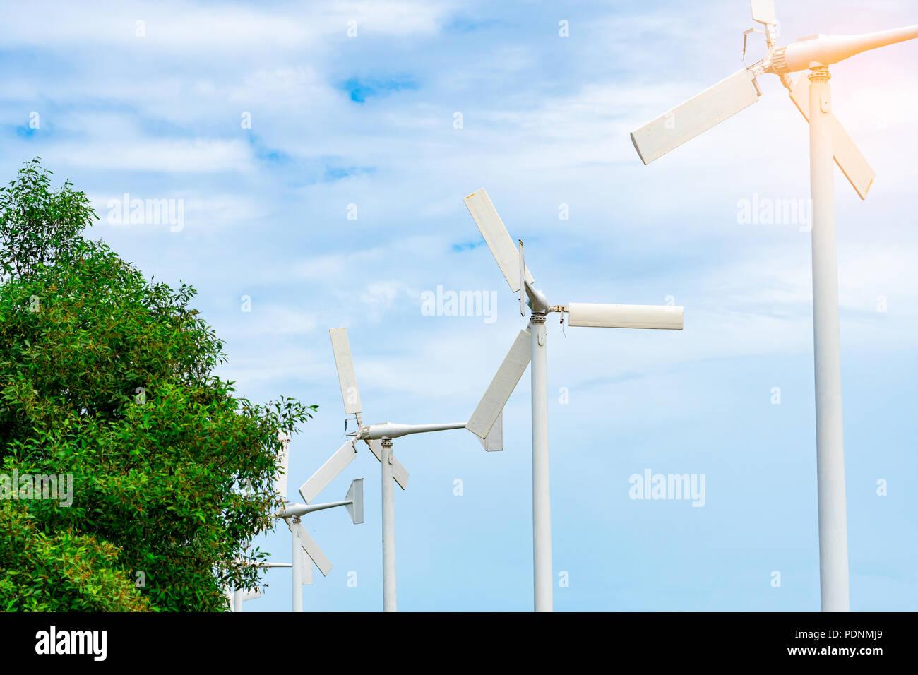 Horizontale Achse Windkraftanlage mit blauem Himmel und weißen Wolken in der Nähe von grünen Bäumen. Windenergie in Eco-Windparks. Grüne Energie Konzept. Erneuerung der Energie. Ändern Stockfoto
