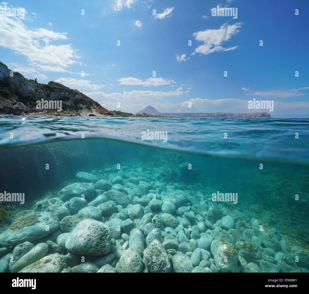 Küste in der Nähe von Javea mit Felsen unter Wasser, geteilte Ansicht oberhalb und unterhalb der Wasseroberfläche, Mittelmeer, Costa Blanca, Alicante, Valencia, Spanien Stockfoto