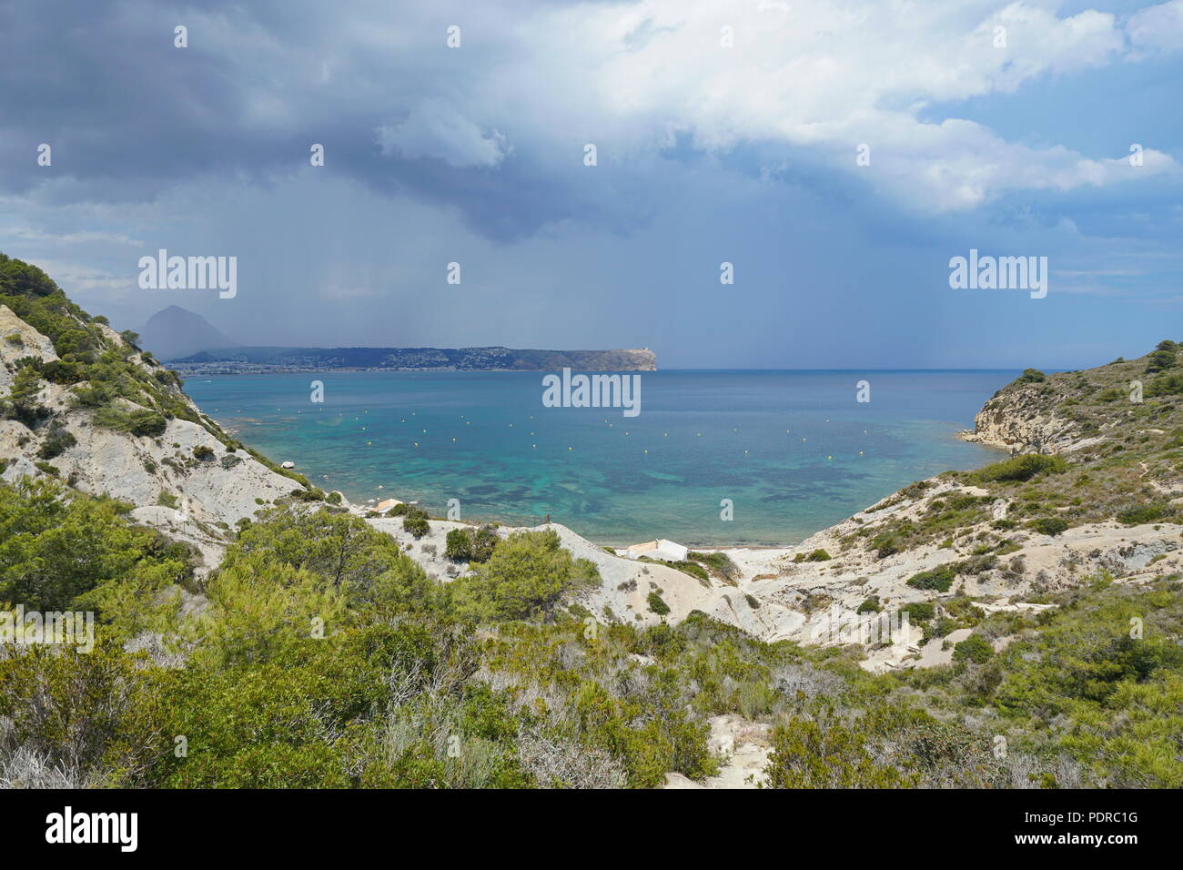 Spanien Javea Bucht Cala Sardinera mit stürmischen Himmel und dem Kap San Antonio im Hintergrund, Mittelmeer, Costa Blanca, Alicante, Valencia Stockfoto
