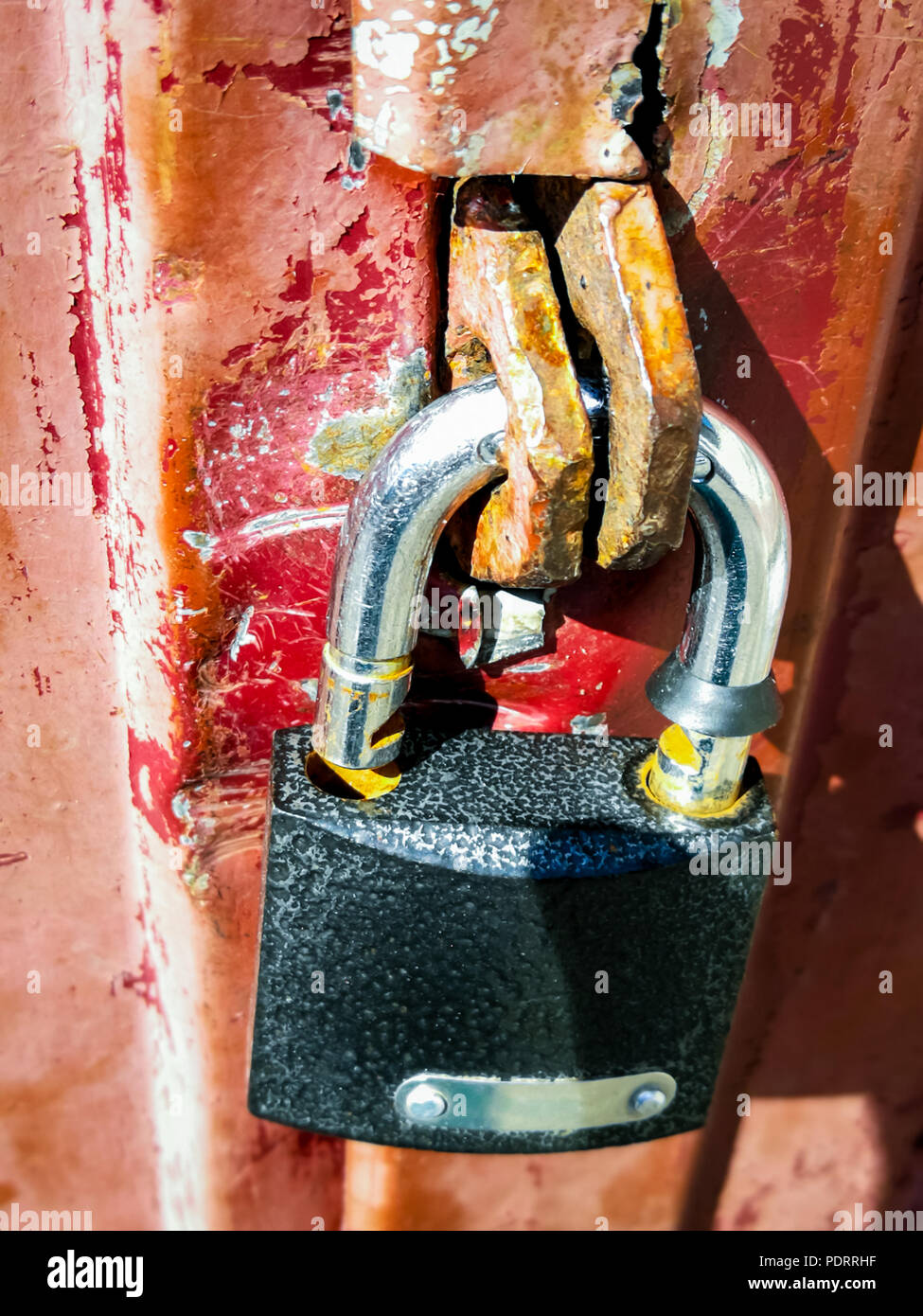 Ein offenes Vorhängeschloss hängt auf einem eisernen Tor. Stockfoto