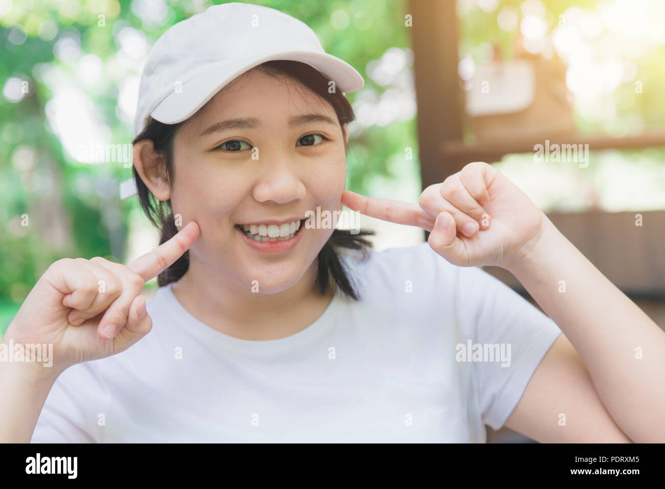 Asiatische cute Teen gute zahnmedizinische Gesundheit lächelnd Finger auf ihre Wangen Stockfoto