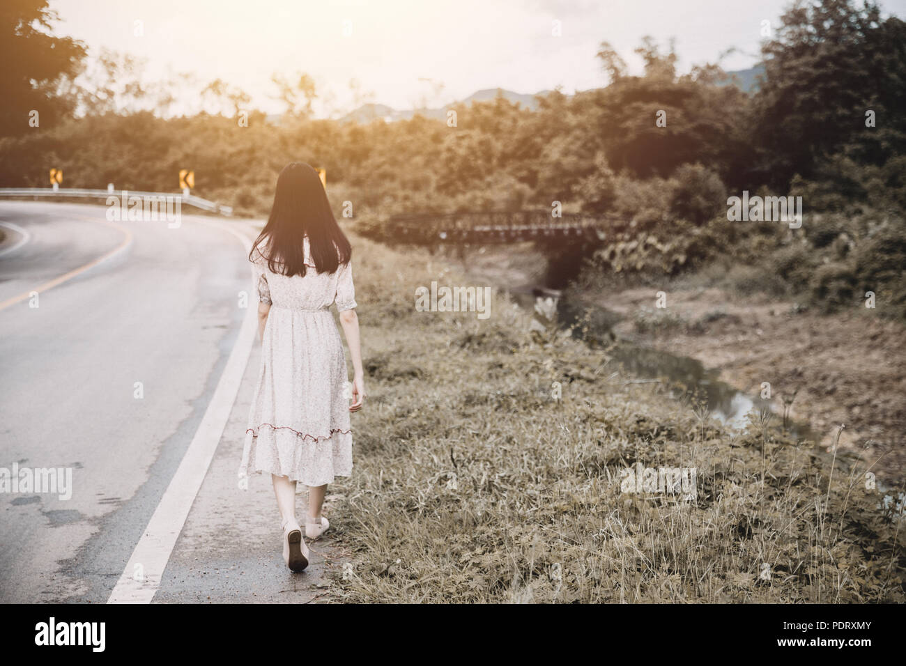 Mädchen zu Fuß allein Frau wandern einsam am Straßenrand Stockfoto