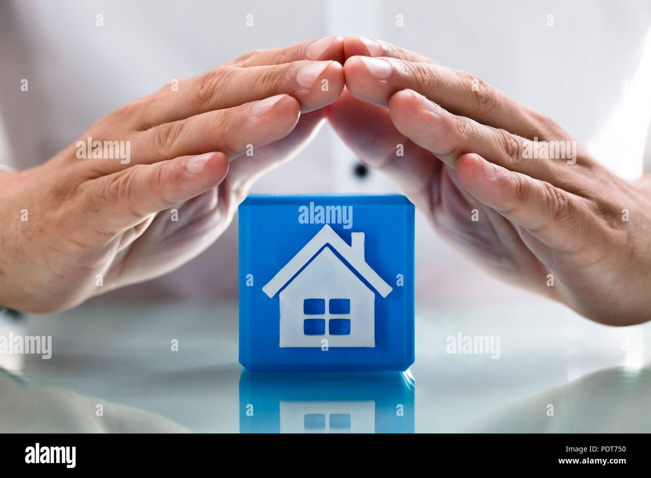 Nahaufnahme einer Hand Schutz blau cubic Block mit Symbol House Stockfoto Nahaufnahme einer Hand Schutz blau cubic Block mit Symbol House Stockfoto
