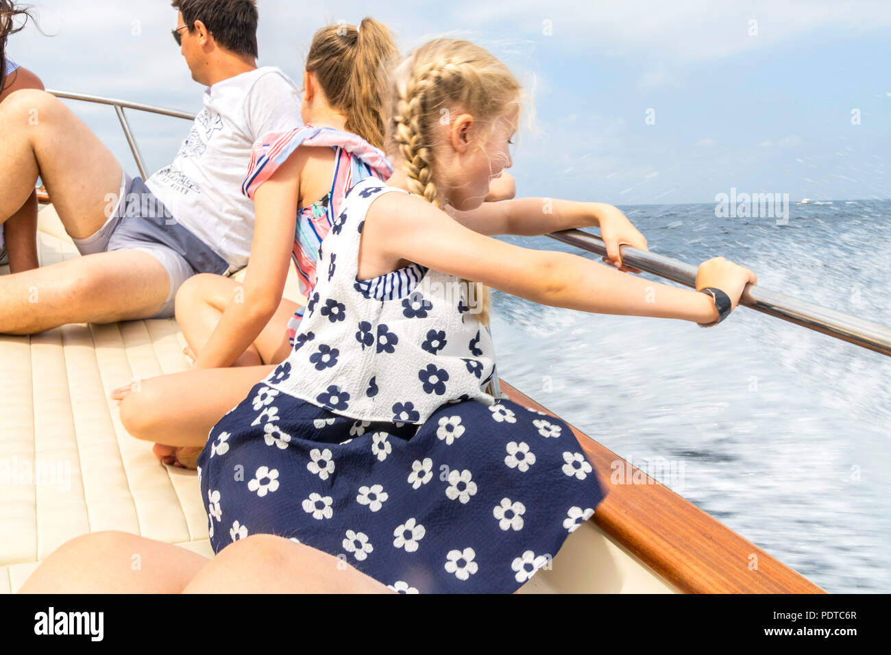 Aufgeregt, happy Girl, Kid, Kind, Sitzen, Yacht, Boot, Wellen mit Schaum auf Seite glücklich awe Wunder Freude Konzept Capri Italien Holding Stockfoto