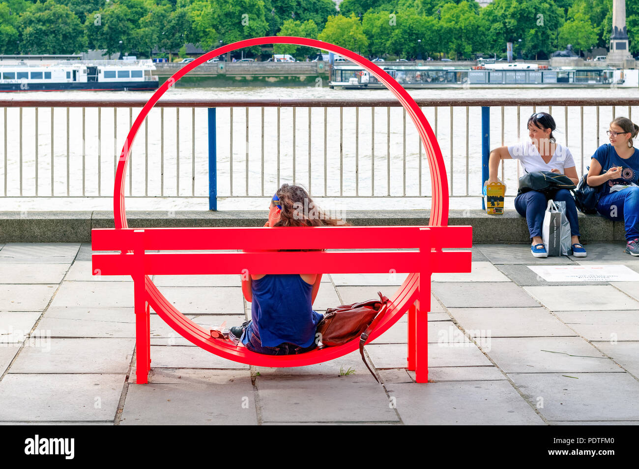 London, Großbritannien - 7 August, 2018 - Touristische sitzen auf einer der veränderten sozialen Bänke von Jeppe Hein in South Bank angezeigt Stockfoto