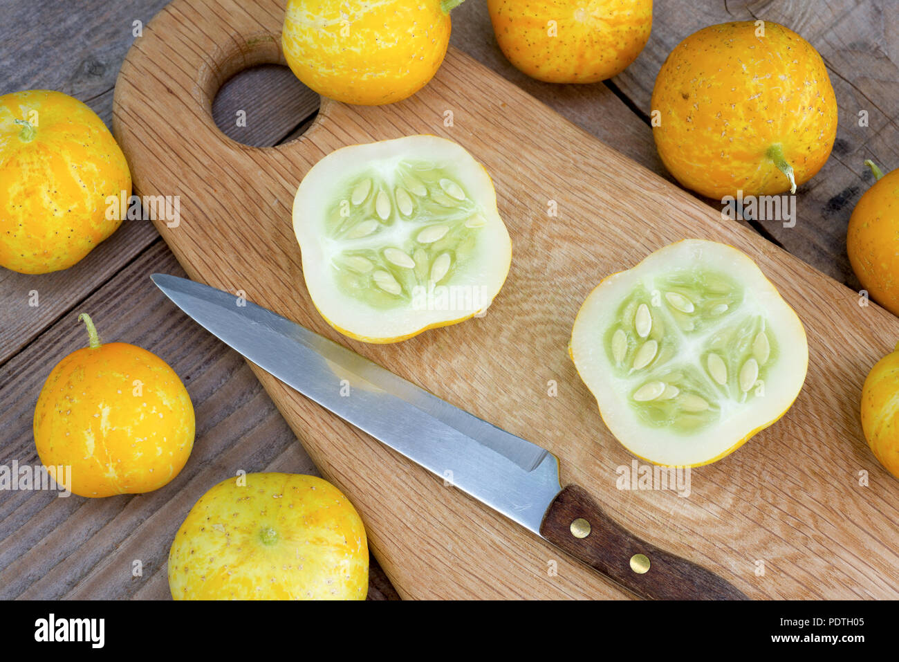 Zitrone Gurken, auch als Cucumis sativus auf einer hölzernen Schneidebrett mit ganzen und schneiden Sie Obst bekannt. Stockfoto