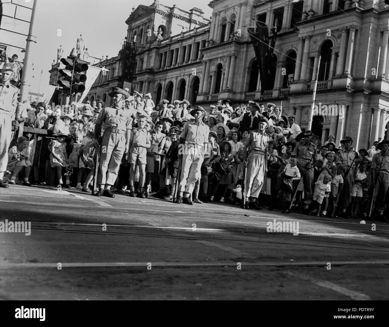 201 StateLibQld 1 104664 kleine Kinder peer Aus zwischen den Soldaten während der Wartezeit für Königin Elizabeth II. und Prinz Philip, März 1954 Stockfoto