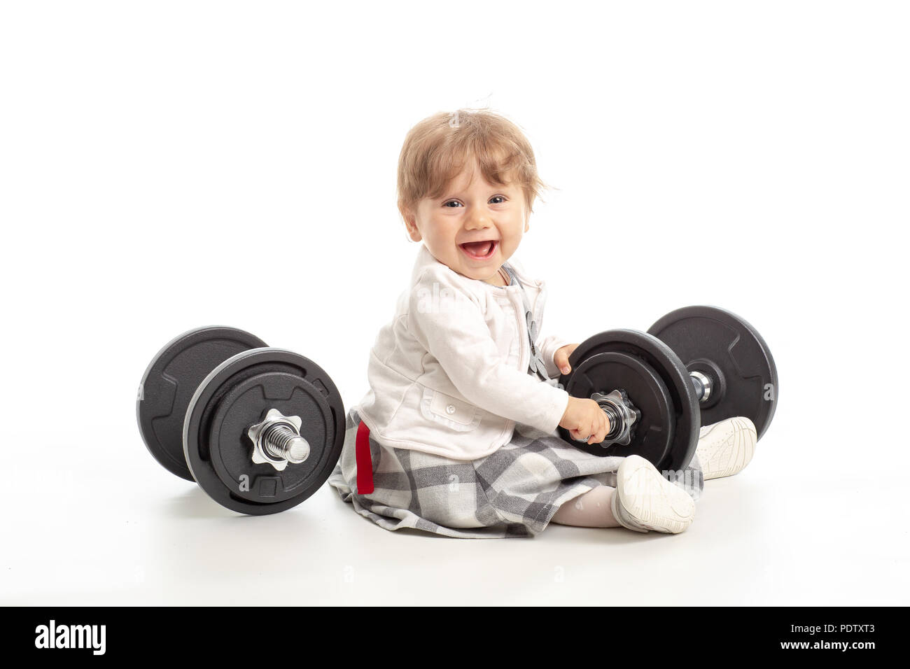 Kleine weibliche Baby spielt mit Fitnessstudio Gewichte im Studio shot auf weißem Hintergrund. Konzept gesunde Leben in der Turnhalle Stockfoto