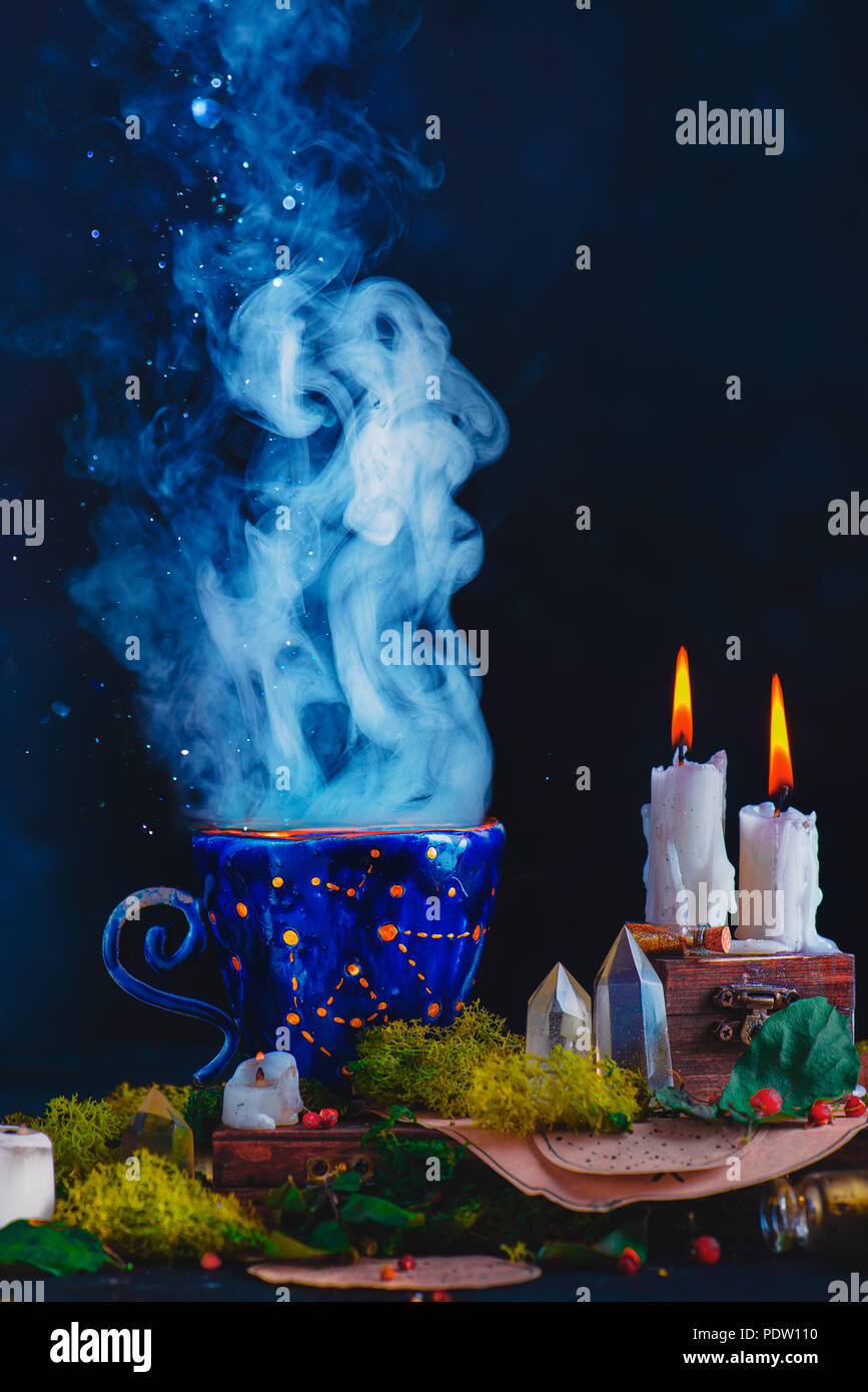 Magische Keramiktasse mit Sternbilder und Sterne in einer dunklen noch leben. Hexe oder astrologe Arbeitsplatz mit brennenden Kerzen, Rauch, Kristalle, Moos und Stockfoto