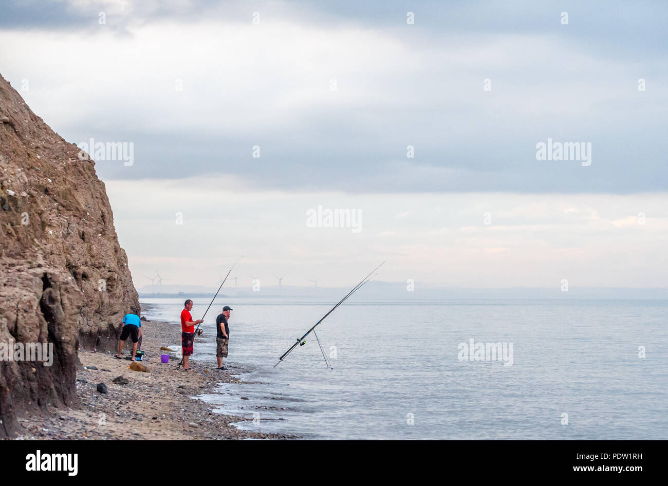 Sea angler Angeln vom Strand von Skipsea, Yorkshire bei Flut, Stockfoto