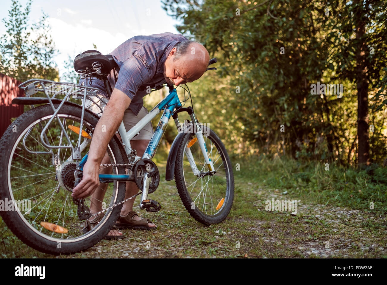 Reifer Mann Probleme mit seinem Fahrrad. Versucht es zu reparieren, während reiten Outdoor im Park. Stockfoto
