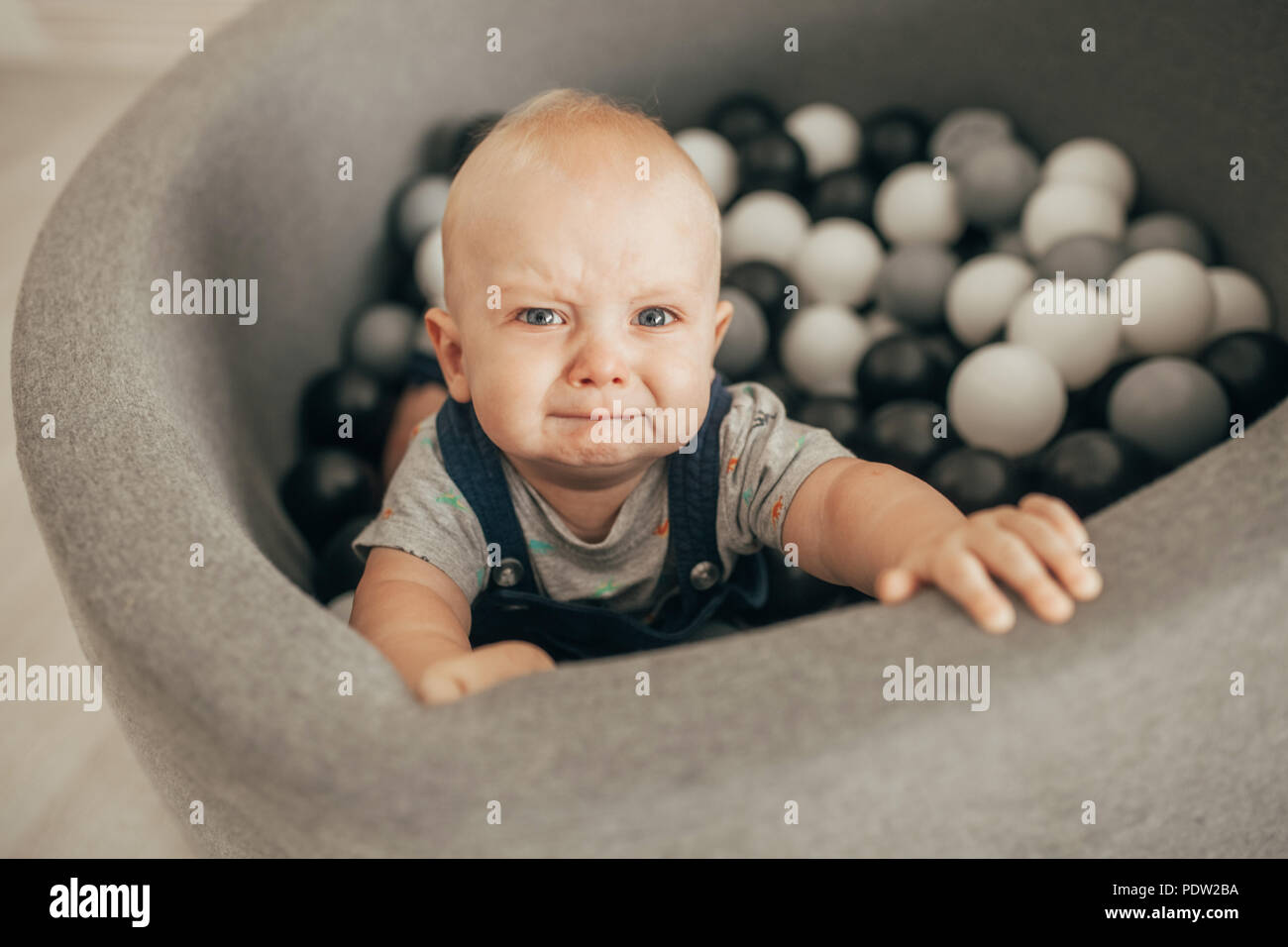 Tränenreich toddler steht in Korb mit kleinen Kugeln und weint. Ansicht von oben. Stockfoto