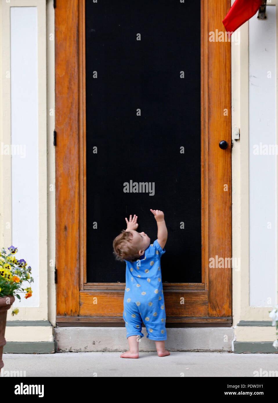 Ein Kleinkind junge erforscht das Innere eines Home, indem man durch das Sieb. Stockfoto