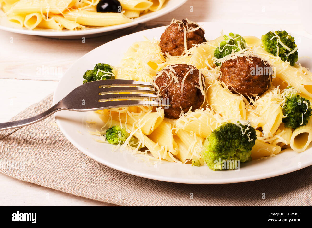 Pasta Penne mit Frikadellen und Brokkoli mit Gabel auf einem Teller Stockfoto