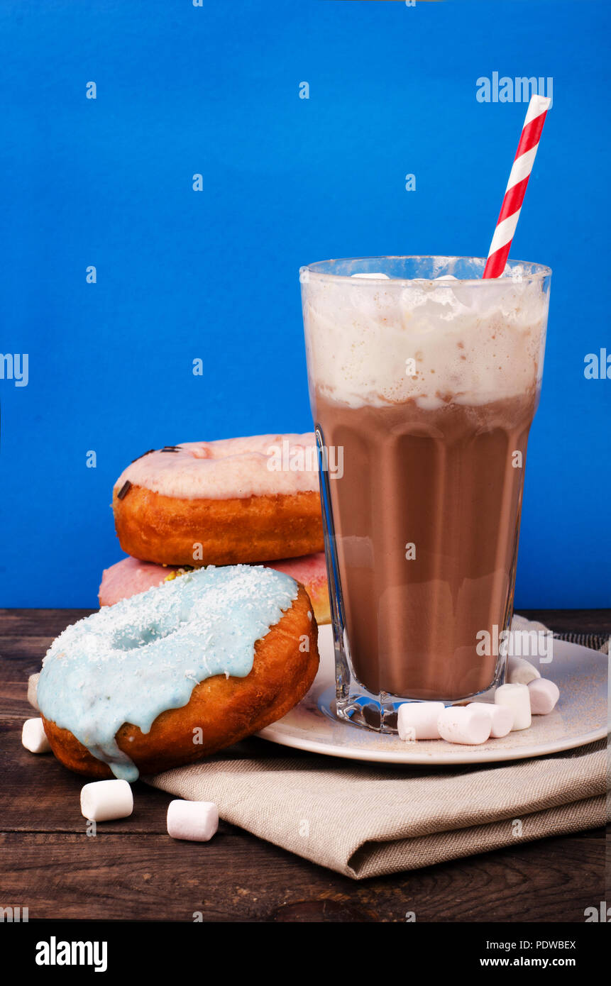 Milchshake und Donuts in Glas auf blauem Hintergrund Stockfoto