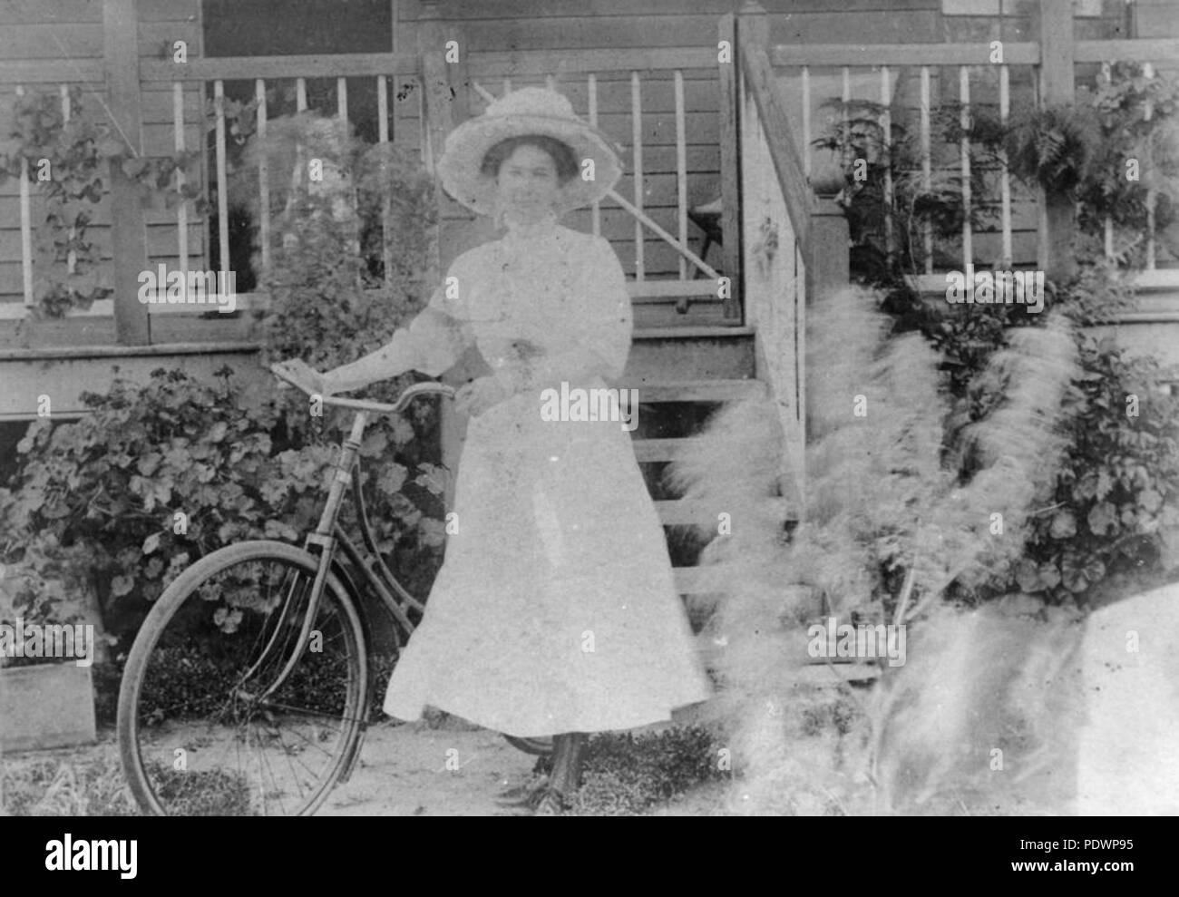 278 StateLibQld 1 99252 Weibliche Radfahrer tragen ein breites geströmter Hut und Kleid, mit Ihrem Fahrrad Posing, Ca. 1908 Stockfoto
