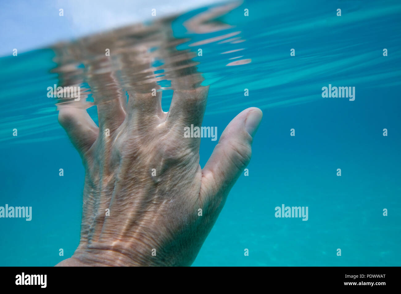 Hälfte ist eine 50 Jahre alte Frau unter Wasser im Meer und die Finger über die Oberfläche des Wassers Stockfoto