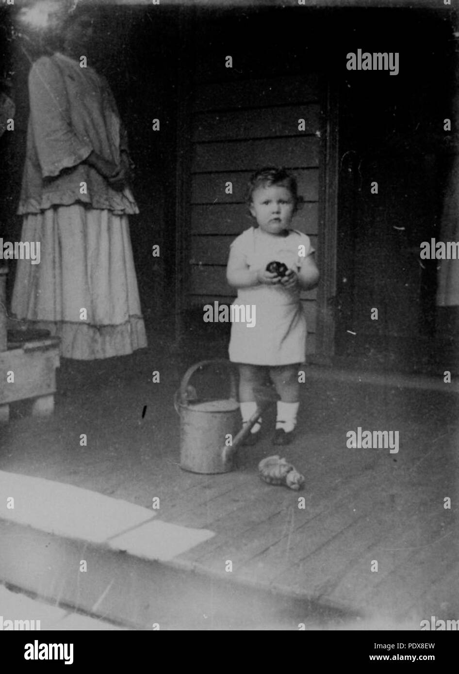 269 StateLibQld 1 63767 Kind auf einer Veranda mit Wasser kann Stockfoto