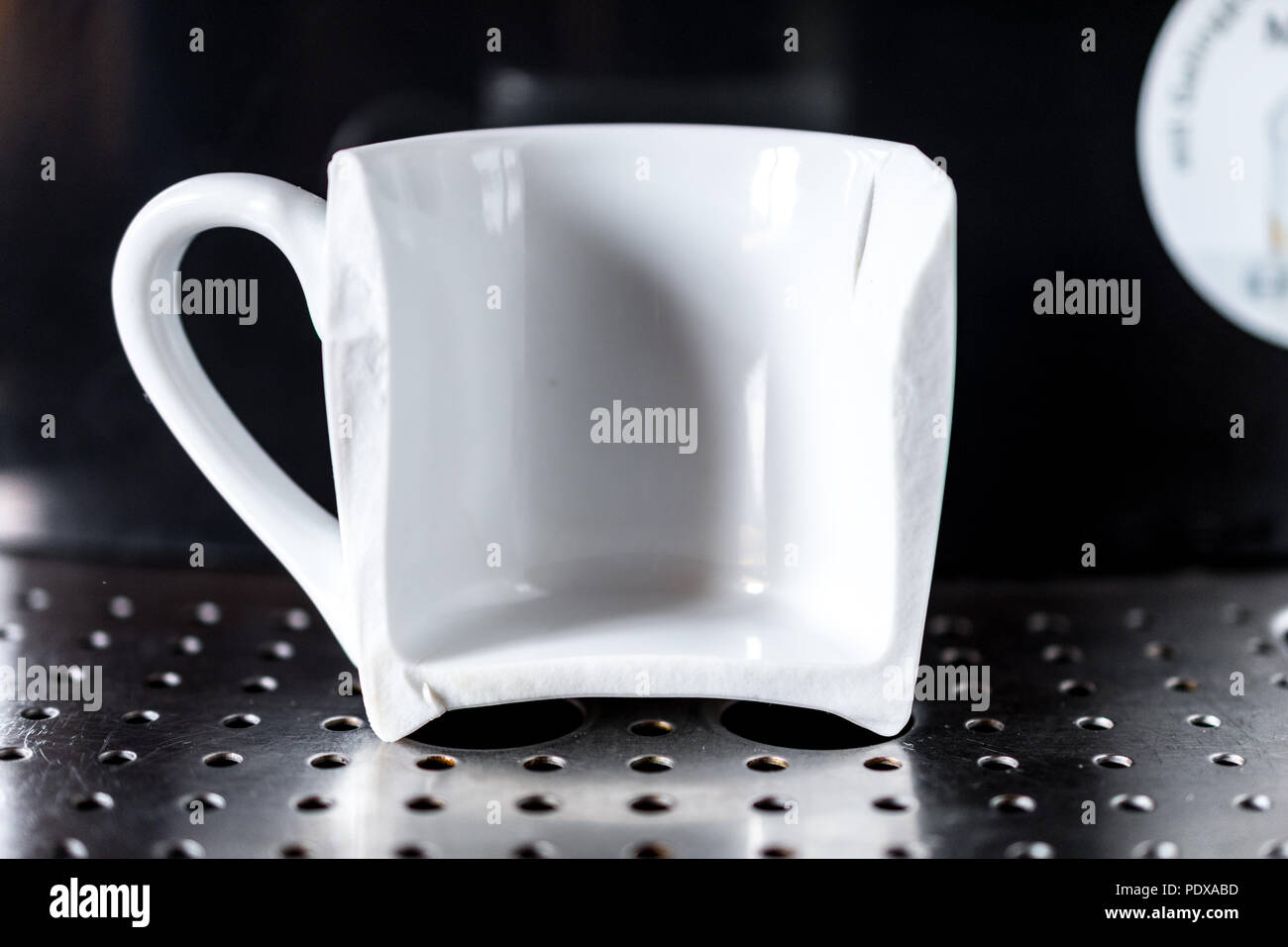 Nahaufnahme auf weißem Espresso Kaffee Tasse zur Hälfte gebrochen an home Espresso Maschine platziert. Konzept der schlechten Morgen Stockfoto