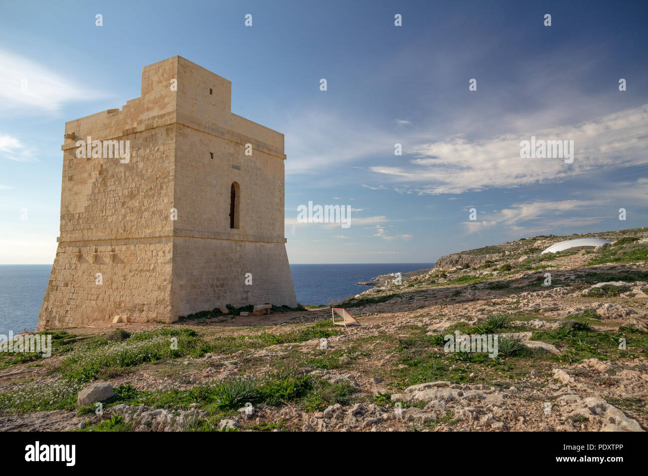 In weiches Licht des Winters am Nachmittag, Tal Hamrija Coastal Tower in der Nähe von Hagar Qim, Malta, steht auf Steilküsten gegen den blauen Himmel und die wispy Himmel Stockfoto