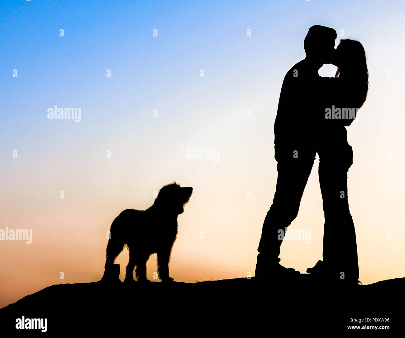 Romantisches Paar bei Sonnenuntergang mit ihrem Hund. Stockfoto