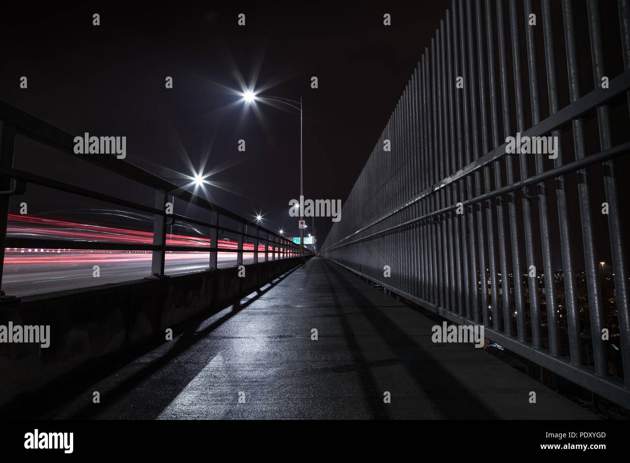 Die Second Narrows Bridge Bürgersteig in der Nacht, mit leichten Spuren von vorbeifahrenden Autos. Stockfoto