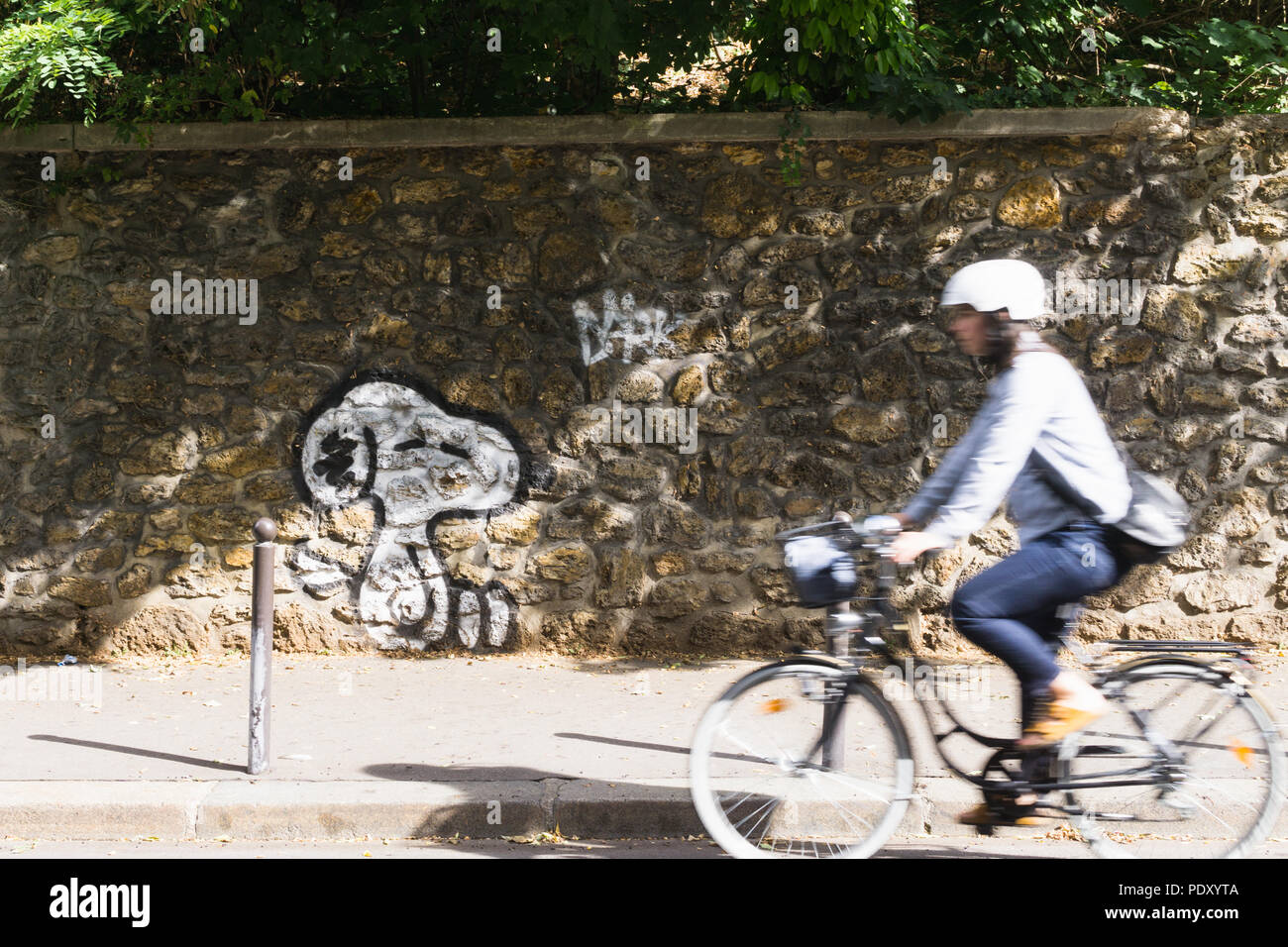 Paris Street Art - Frau Radfahren durch die Snoopy Graffiti an einer Wand in Belleville Viertel von Paris, Frankreich, Europa. Stockfoto