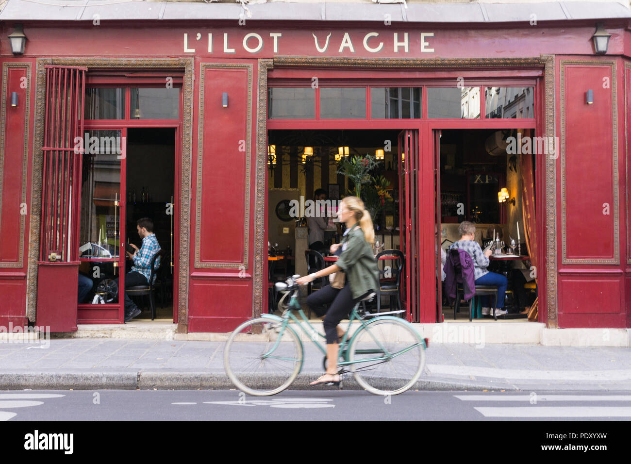 Paris mit dem Fahrrad - eine Frau, Radfahren an der L'Ilot Vache Restaurant auf der Ile de la Cite in Paris, Frankreich, Europa. Stockfoto