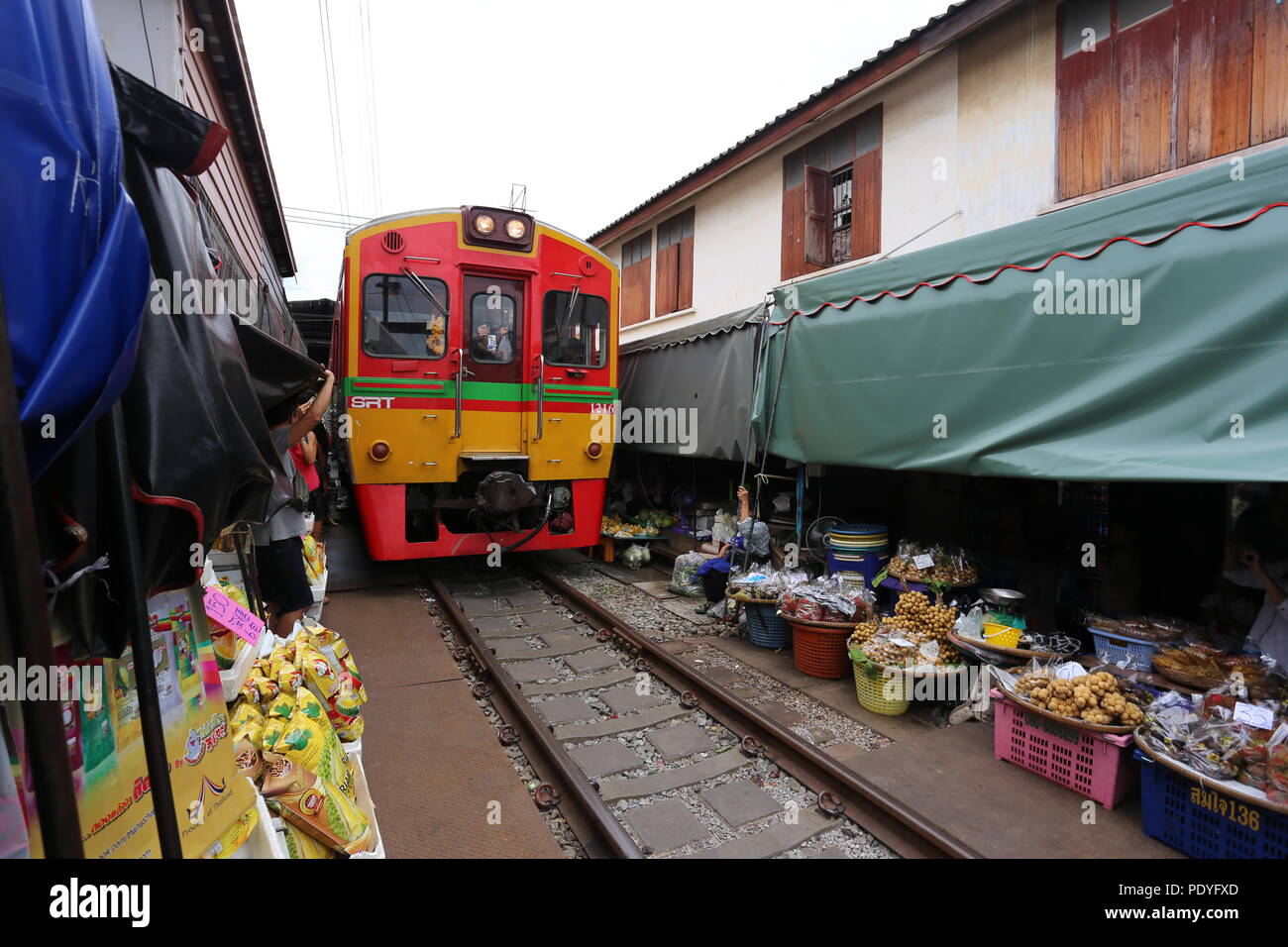 Ein Zug fährt durch Maeklong Markt als Anbieter einen Pfad löschen und dann die Markisen nach unten klappen nach dem Es geht. Es ist, als der Schirm Markt bekannt. Stockfoto