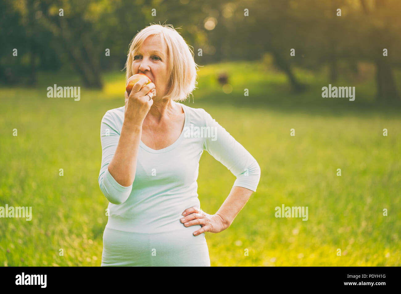 Active Senior Frau essen Apple nach Übung. Bild ist absichtlich abgeschwächt. Stockfoto