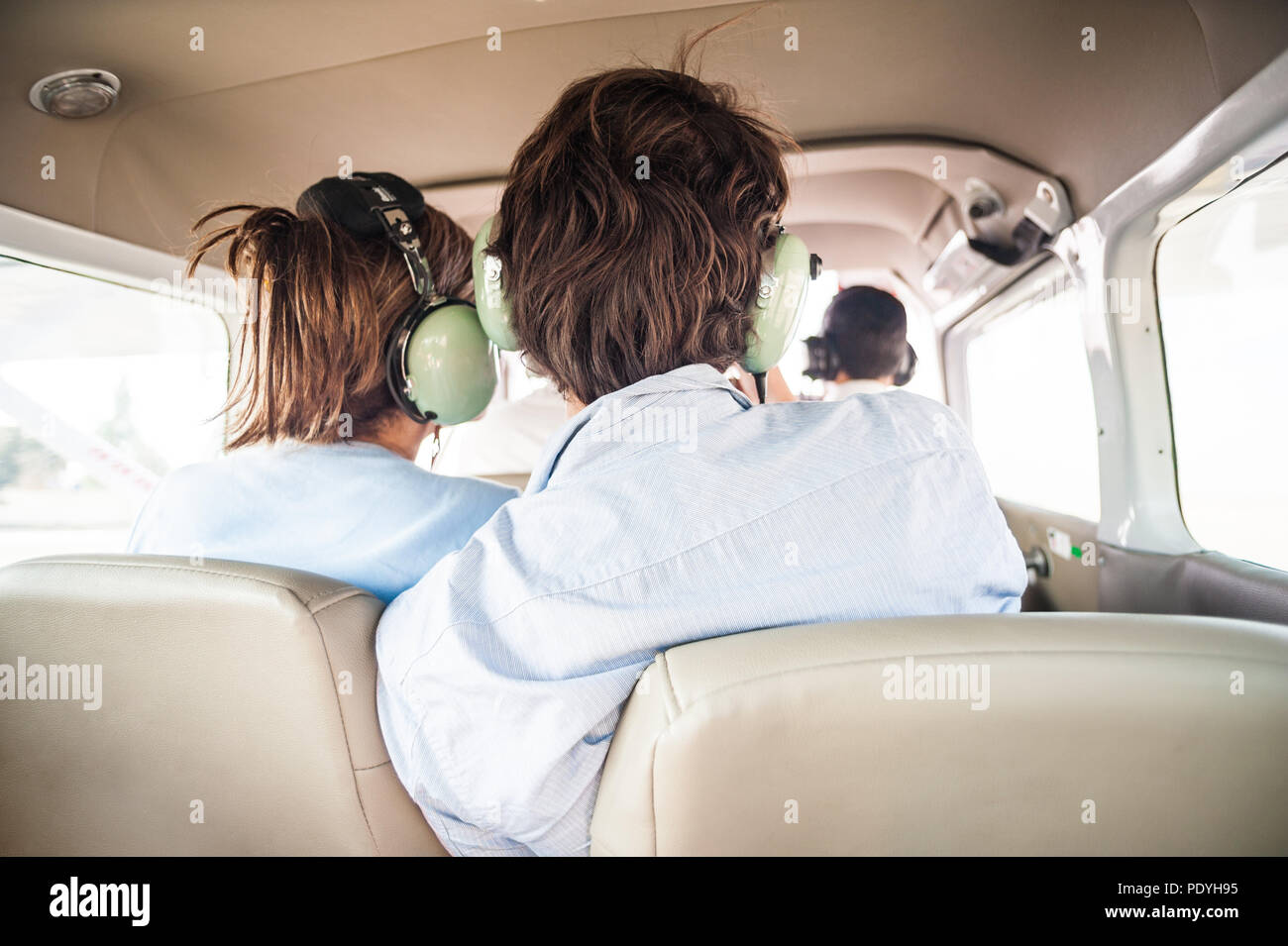 Junge touristische Paar, eine kleine Fläche. Das Tragen von Headsets und Miteinander zärtlich während des Fluges. Stockfoto