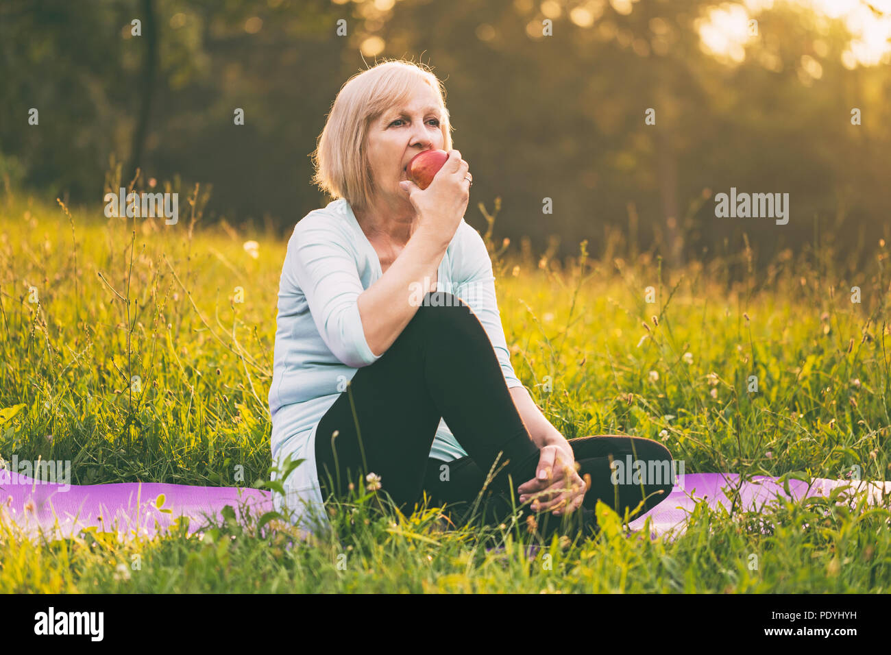Active Senior Frau essen Apple nach Übung. Bild ist absichtlich abgeschwächt. Stockfoto
